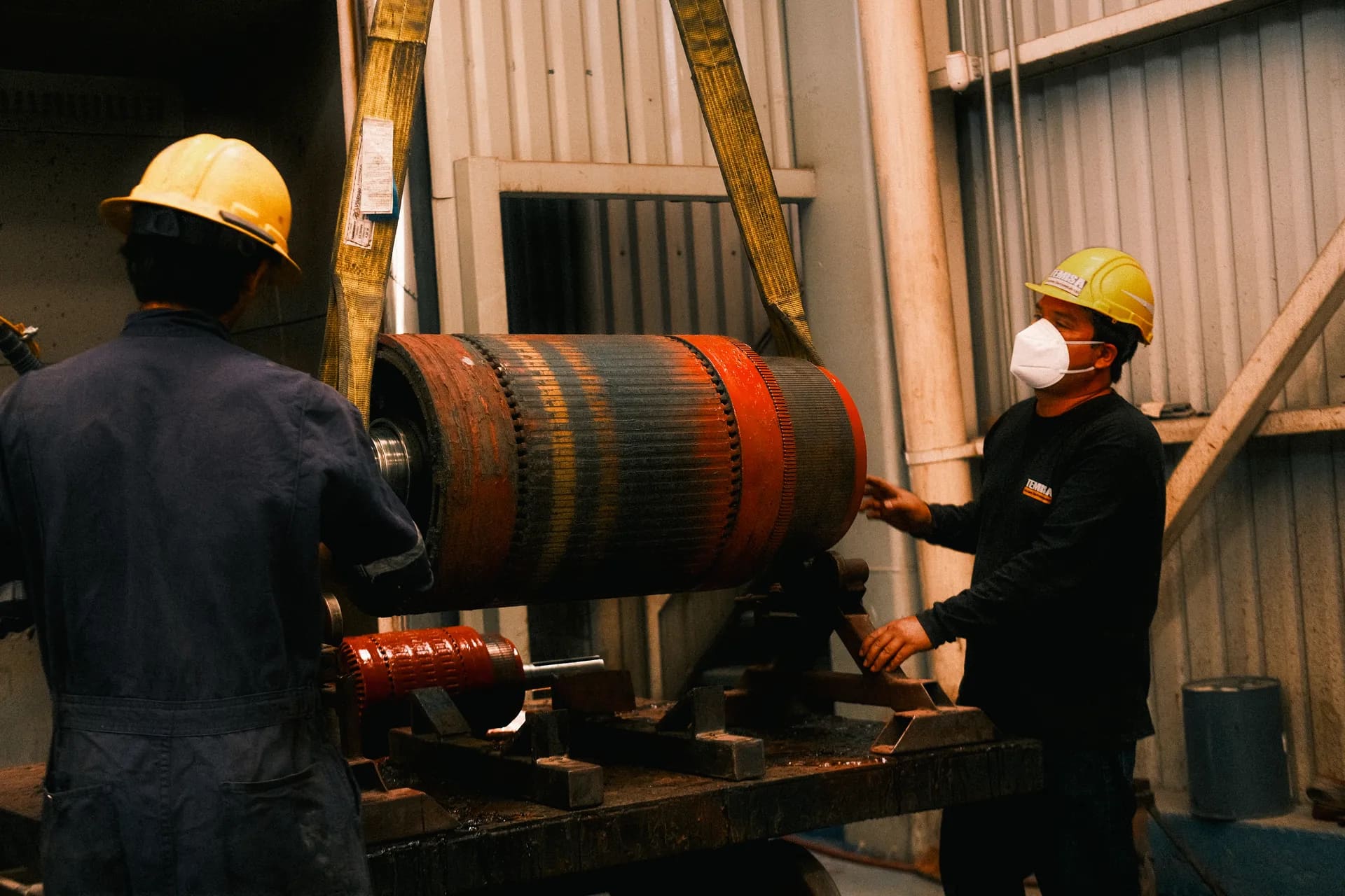 Técnicos de TEMISA maniobrando la armadura de un motor de tracción ferroviaria en el taller