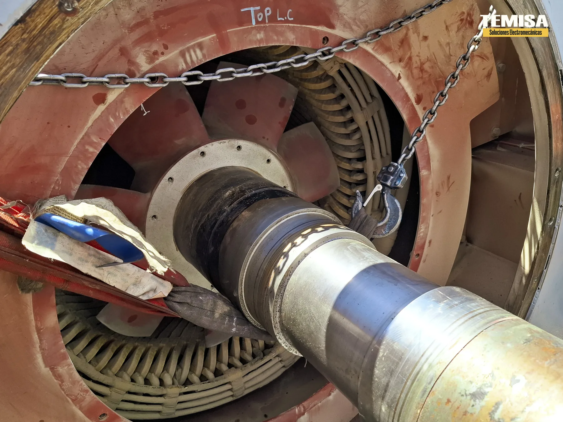 Rotor de un motor de gran potencia siendo extraído del estator con eslingas y cadenas, con el devanado del estator visible al fondo