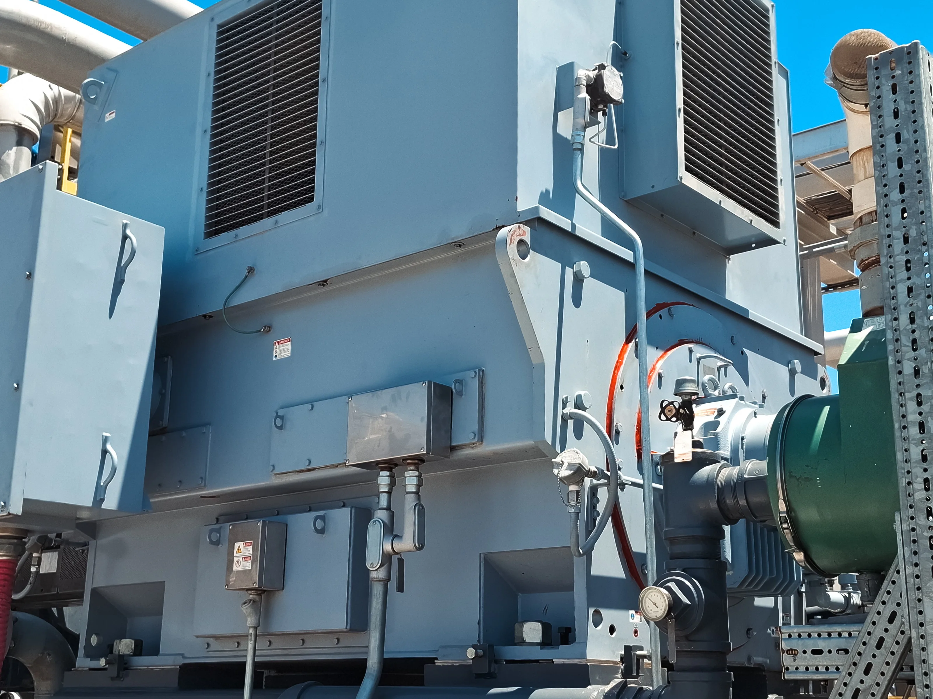 Motor eléctrico de gran potencia con sus intercambiadores de calor aire-aire montados sobre la carcasa, instalado a la intemperie en una planta de proceso