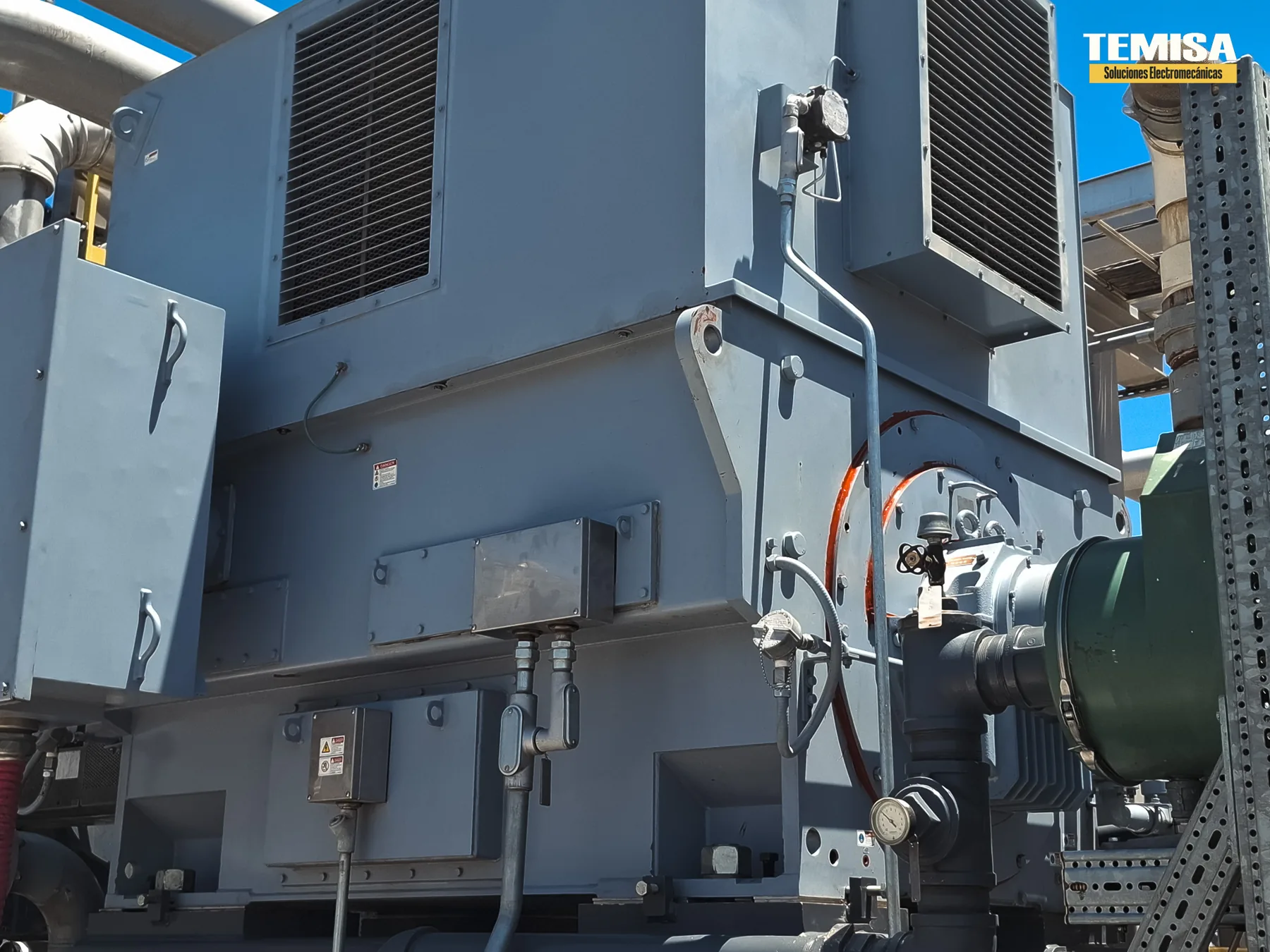 Motor eléctrico de gran potencia con sus intercambiadores de calor aire-aire montados sobre la carcasa, instalado a la intemperie en una planta de proceso