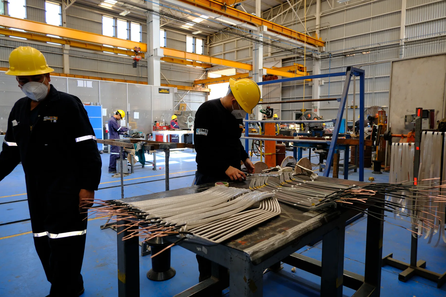 Técnicos acomodando bobinas preformadas en banco de trabajo del taller
