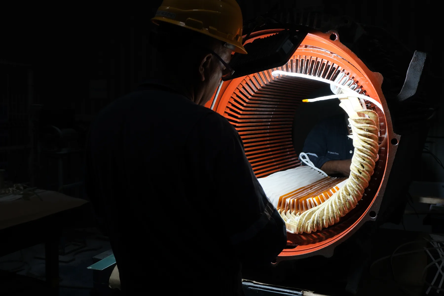 Técnico de TEMISA observando el interior de un estator de motor iluminado durante un rebobinado, sector manufactura