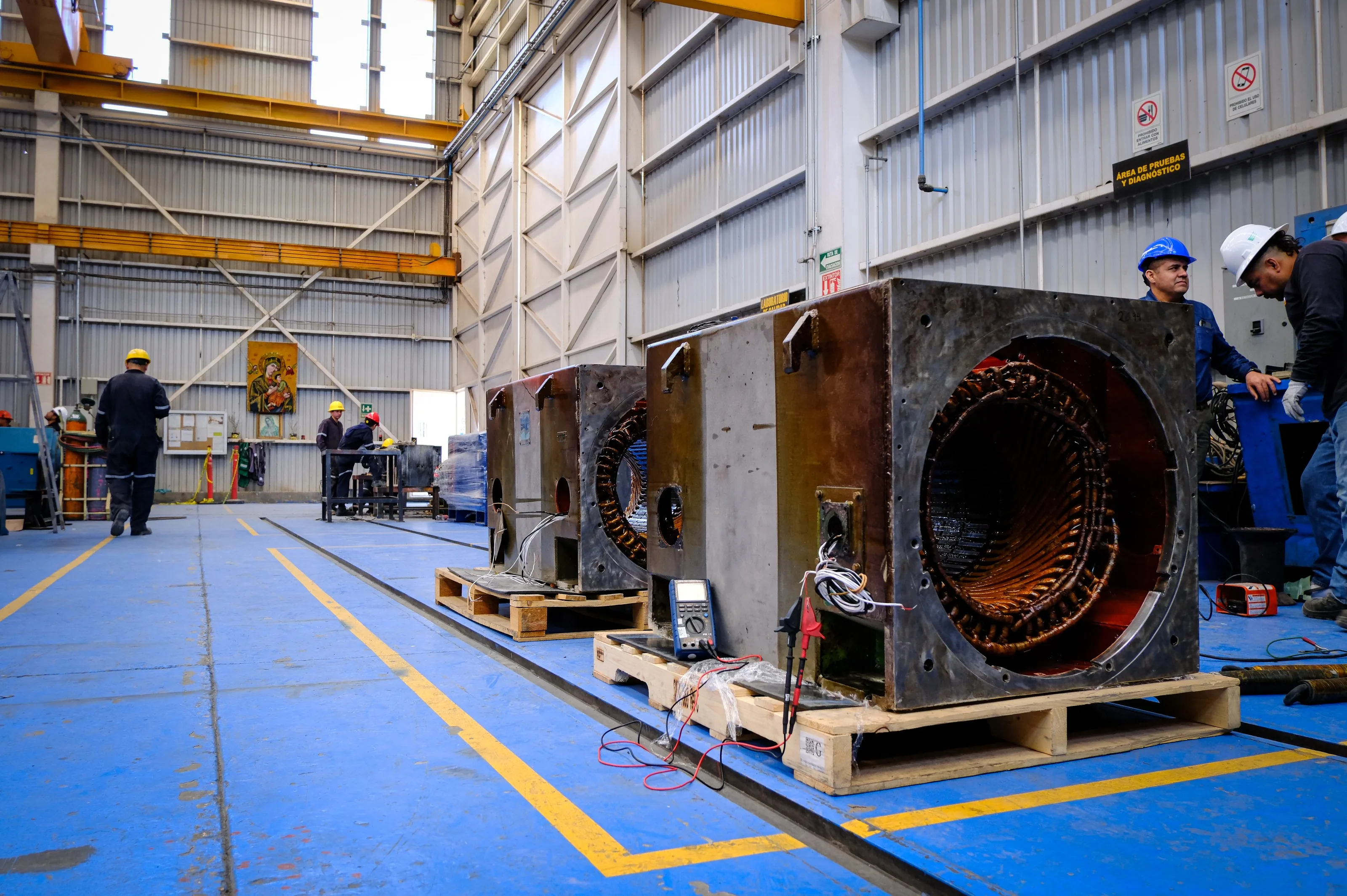 Medición eléctrica a dos estatores de motor sobre tarima, con la cuadrilla y los instrumentos al lado