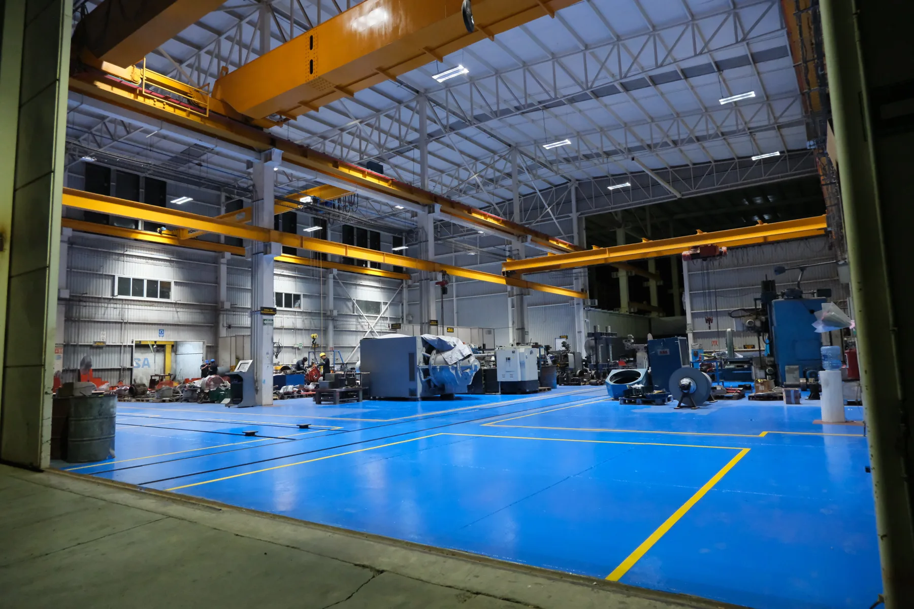 Interior de la nave del taller TEMISA con piso epóxico azul y grúas viajeras dobles
