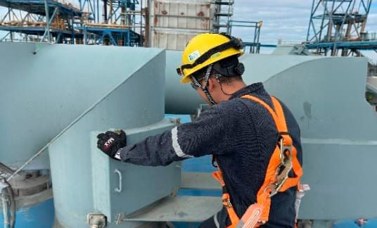 Técnico con arnés ejecutando limpieza en turbogenerador Mitsubishi de 189 MVA en central de ciclo combinado