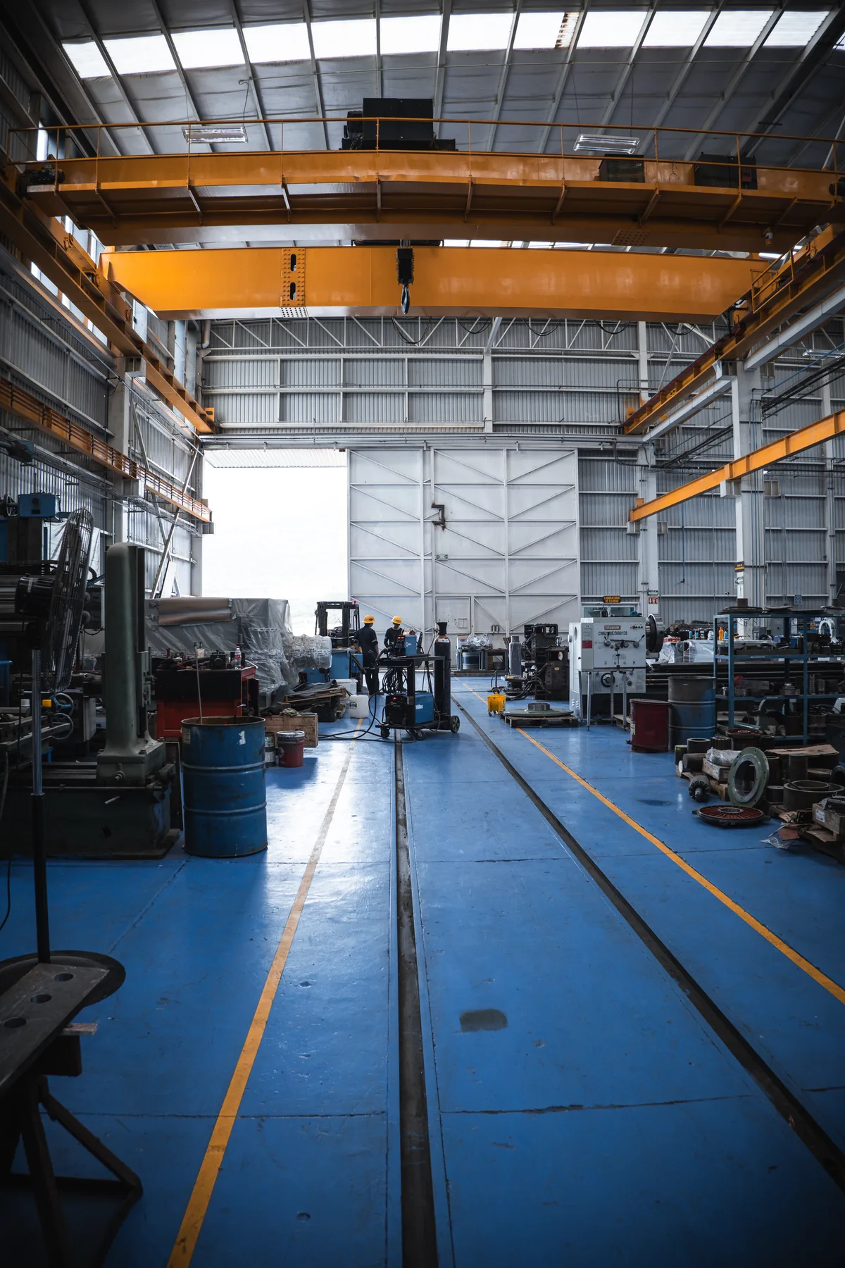 Interior de la nave del taller TEMISA con dos puentes grúa viajeros sobre piso azul con vía de rodamiento