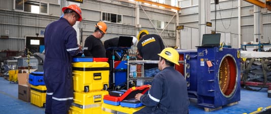 Cuadrilla de TEMISA con maletas de instrumentación y laptops alrededor de una máquina rotativa durante una jornada de pruebas eléctricas